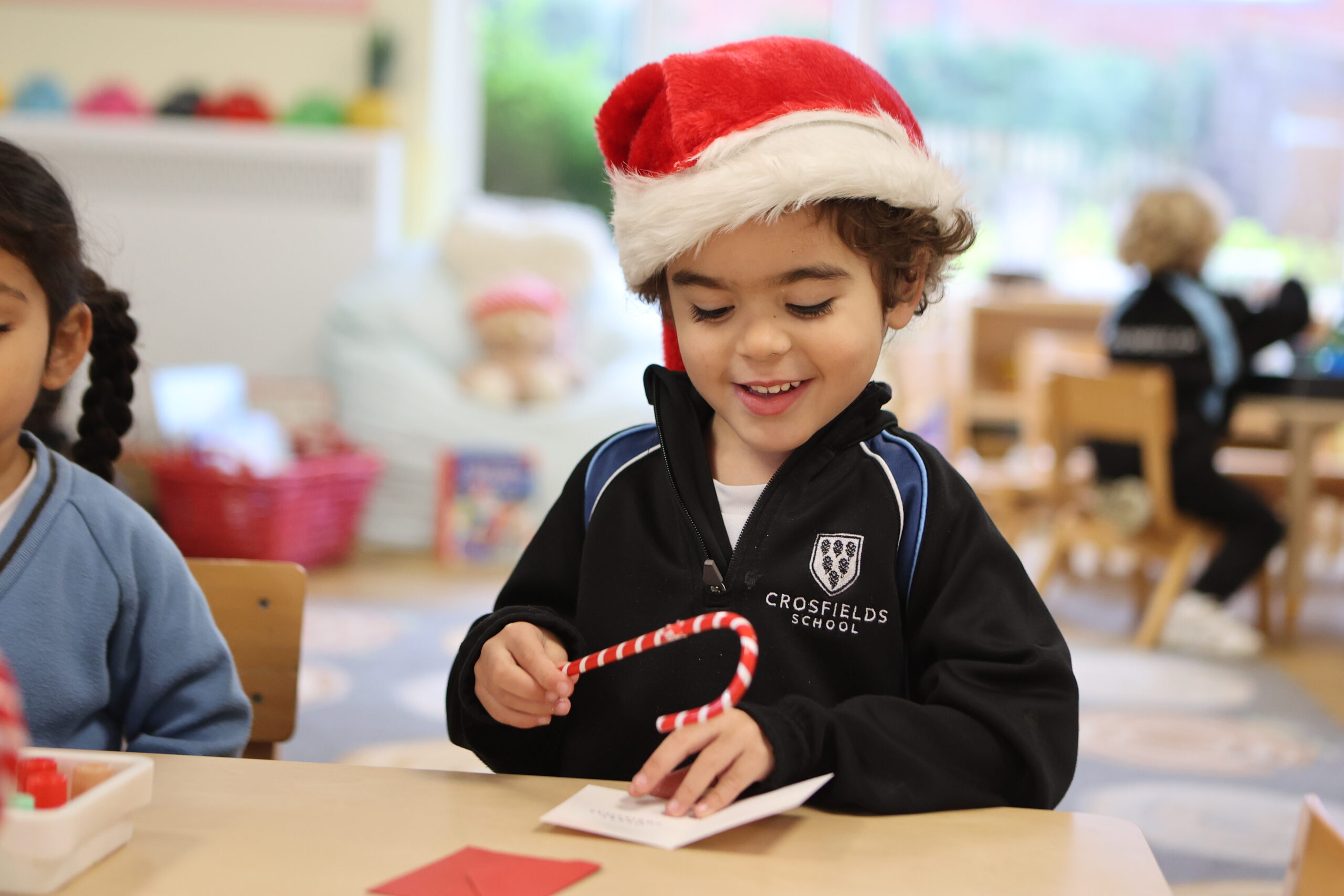 Nursery child at Crosfields School in Reading playing with Santa and a candy cane during the Christmas celebration